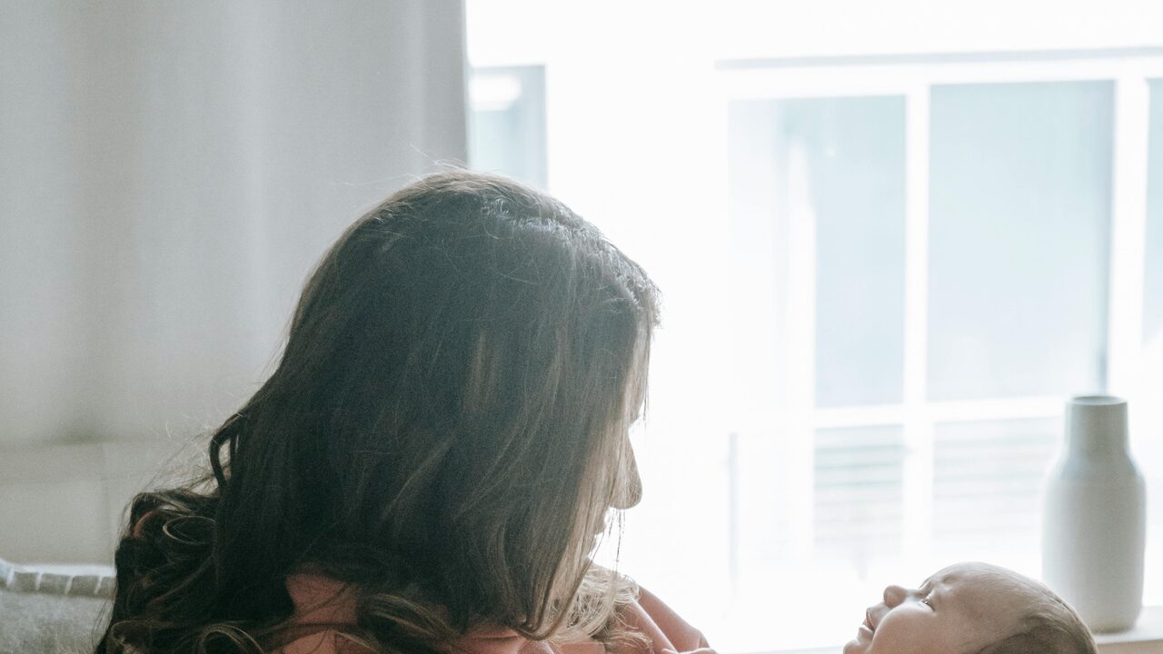 A mother lovingly holding her newborn in a softly lit home setting